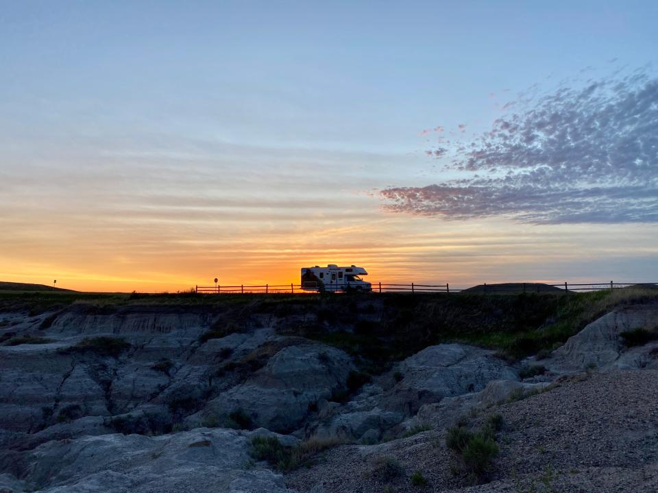 The RV is parked as the sun rises at Badlands National Park.