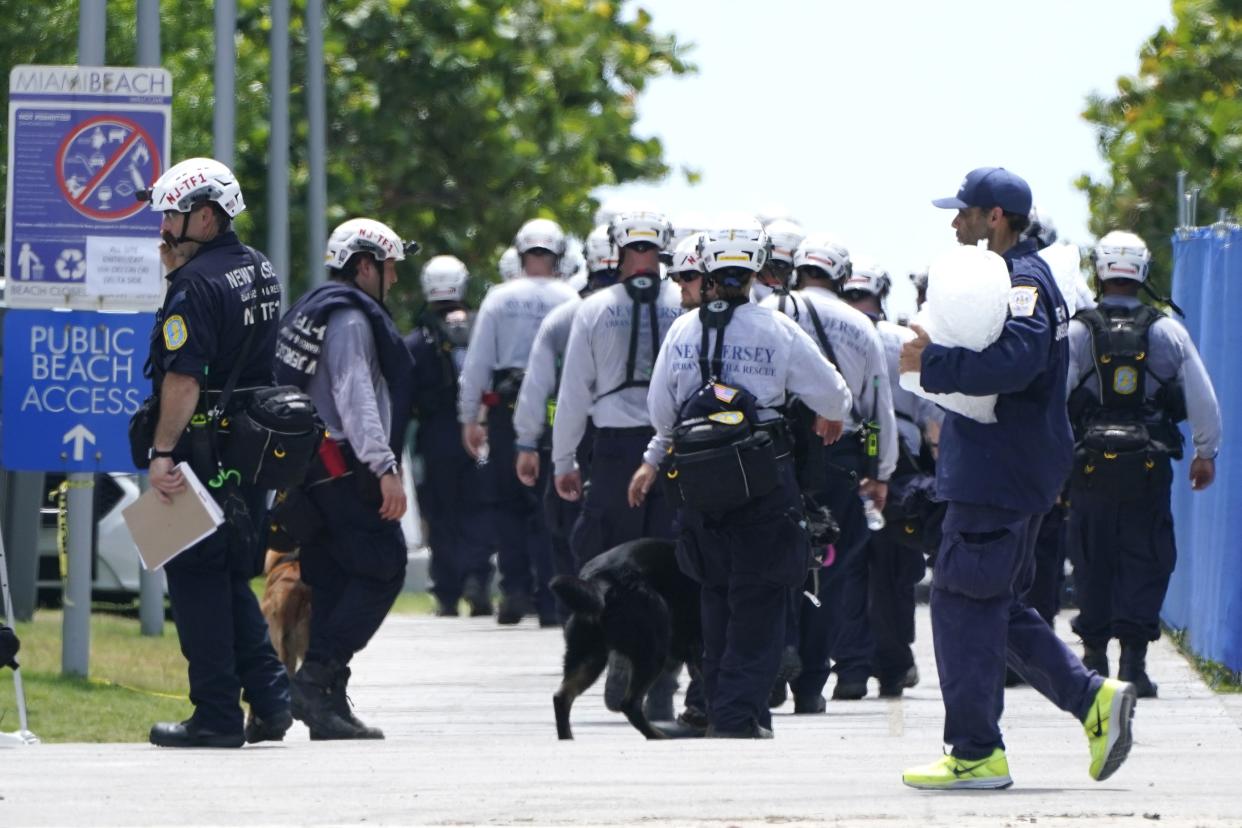 A search and rescue team from New Jersey walks near the Champlain Towers South condo building, where scores of victims remain missing more than a week after it partially collapsed, Sunday, July 4, 2021, in Surfside, Fla.