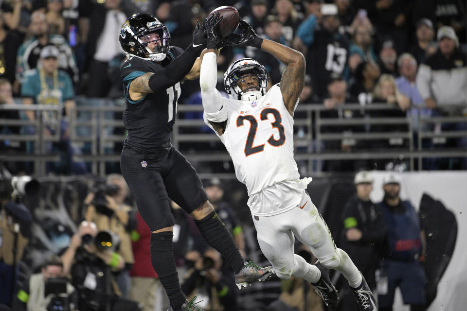 CORRECTS TO SECOND HALF NOT FIRST HALF - Jacksonville Jaguars wide receiver Parker Washington (11) grabs a pass in the end zone for a touchdown as Cincinnati Bengals safety Dax Hill (23) defends during the second half of an NFL football game Monday, Dec. 4, 2023, in Jacksonville, Fla. (AP Photo/Phelan M. Ebenhack)