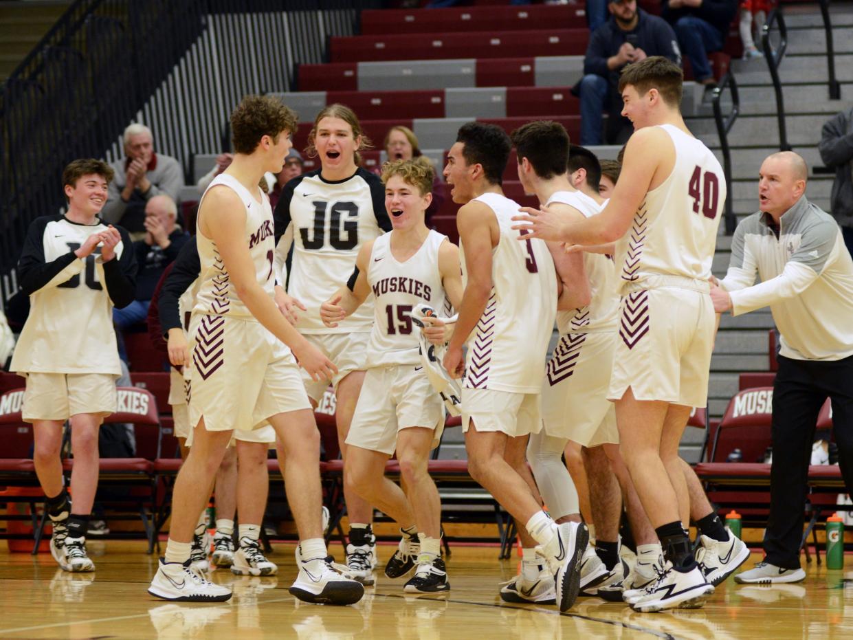 Nathan Walker, left, is congratulated by teammates after hitting three free throws to force overtime against visiting River View on Tuesday night in New Concord. Walker had 28 points as the Muskies won, 93-82, in double overtime.