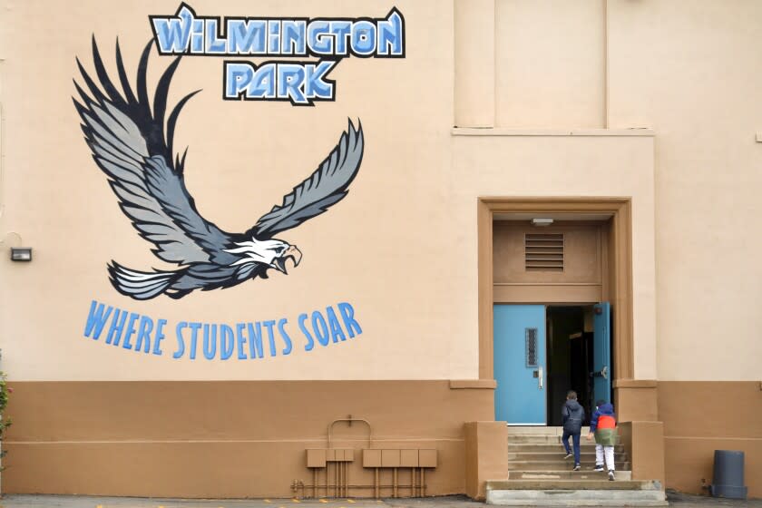 Wilmington, Los Angeles, California-Dec. 7, 2021-Students walk to class through the playground at Wilmington Park Elementary on Dec. 7, 2021, where a 9-year-old girl was hit by a stray bullet yesterday afternoon, Dec. 6, 2021. A 13-year-old boy was killed and two other people were injured, including a 9-year-old girl, in a shooting in Wilmington late Monday afternoon. A 9-year-old girl playing nearby at Wilmington Park Elementary School was hit by a stray bullet, prompting a separate 911 call. She was hospitalized in critical condition. (Carolyn Cole / Los Angeles Times)