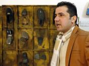 Iraqi artist Akeel Khreef stands in front of his art pieces depicting jihadists made on worn-out shoes on January 13, 2015 at his workshop in Baghdad