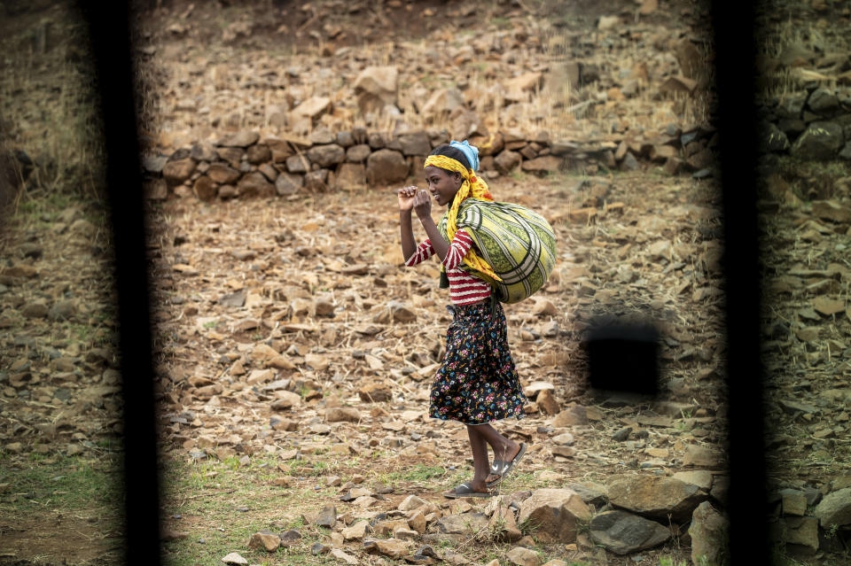 A girl walks by the side of the road, seen through a partially-open window of a vehicle, between Gondar and Danshe, a town in an area of western Tigray annexed by the Amhara region during the ongoing conflict, in Ethiopia Saturday, May 1, 2021. Ethiopia faces a growing crisis of ethnic nationalism that some fear could tear Africa's second most populous country apart, six months after the government launched a military operation in the Tigray region to capture its fugitive leaders. (AP Photo/Ben Curtis)