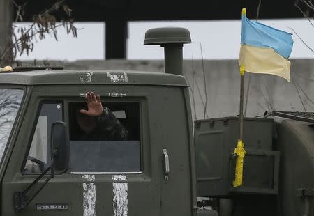 A member of the Ukrainian armed forces waves as he rides on a military vehicle near Artemivsk, eastern Ukraine, March 3, 2015. REUTERS/Gleb Garanich