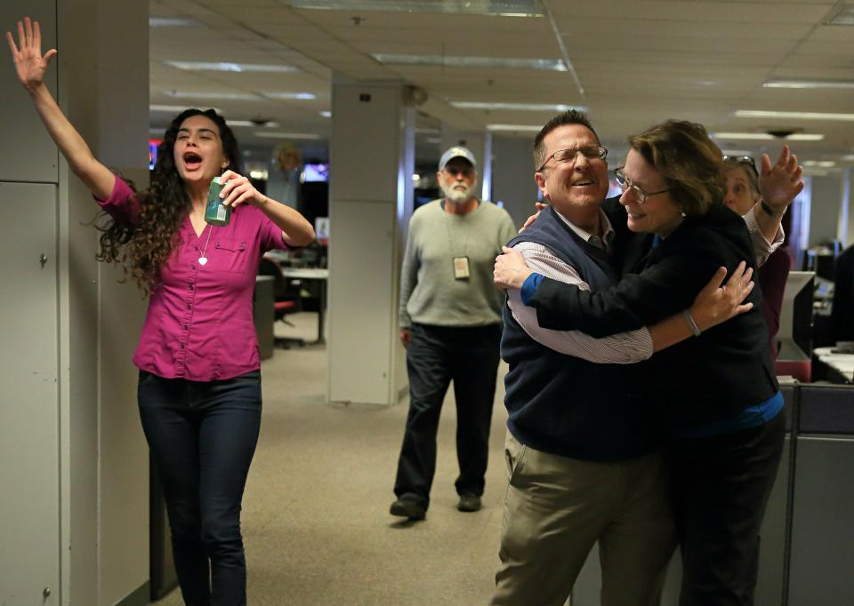 St. Louis Post-Dispatch metro columnist Tony Messenger, center, reacts as he turns towards his editor Marcia L. Koenig in the newsroom at the St. Louis Post-Dispatch in St. Louis, Mo. after it was announced Messenger won the 2019 Pulitzer Prize in Commentary Monday, April 15, 2019. (David Carson/St. Louis Post-Dispatch via AP)