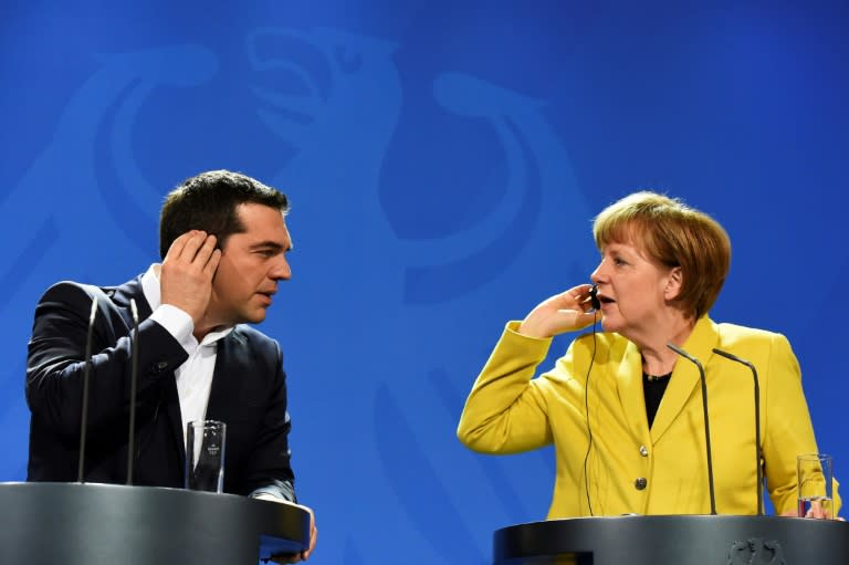 Greek Prime Minister Alexis Tsipras and Merkel use earpieces to understand each other via translators