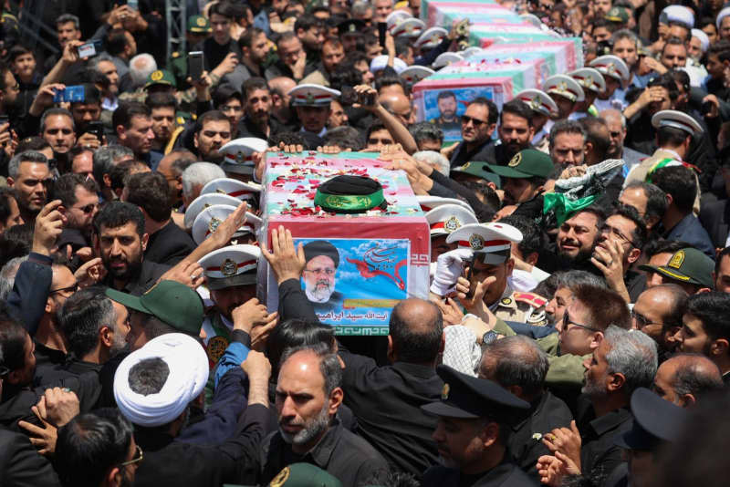 Mourners carry the flag-draped coffins of late Iranian President Ebrahim Raisi, Foreign Minister Hossein Amir-Abdollahian and others killed in a helicopter crash on Sunday during their funeral ceremony in the city of Mashhad.  -/Iranian Presidency/dpa