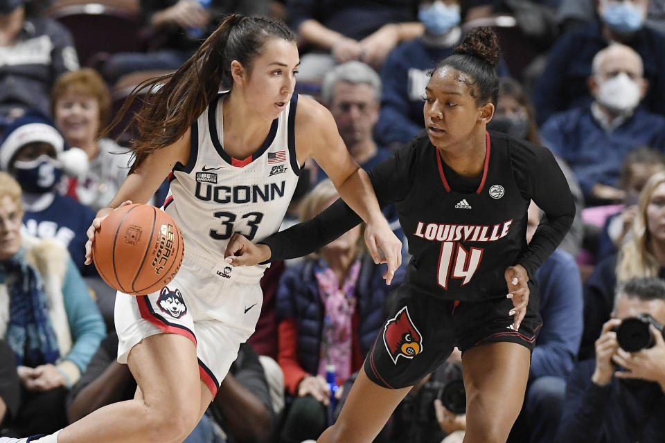 Connecticut's Caroline Ducharme (33) dribbles as Louisville's Kianna Smith (14) defends in the second half of an NCAA college basketball game, Sunday, Dec. 19, 2021, in Uncasville, Conn. (AP Photo/Jessica Hill)