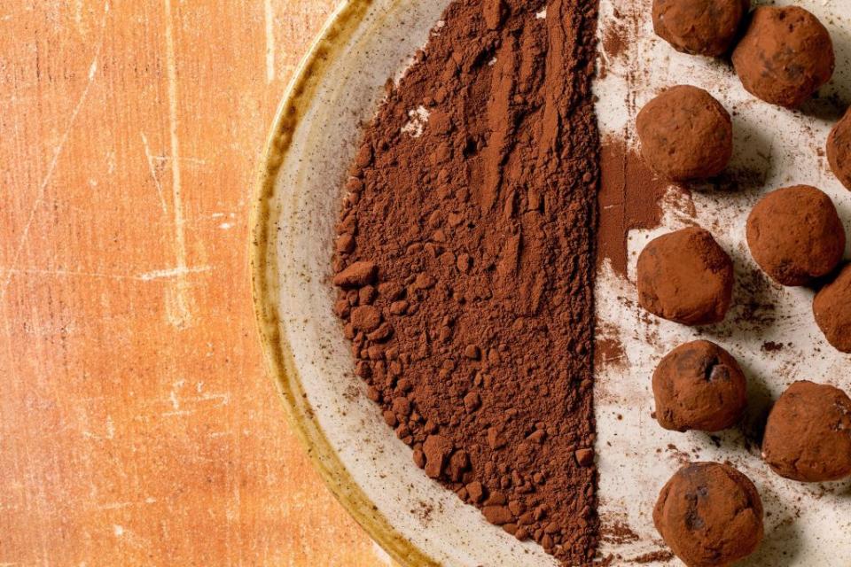 homemade dark chocolate cocoa truffle candy and cocoa powder on ceramic plate over stone background handmade food sweet gifts for any holidays top view, copy space