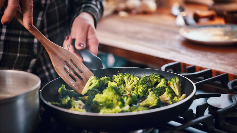 Person cooking broccoli