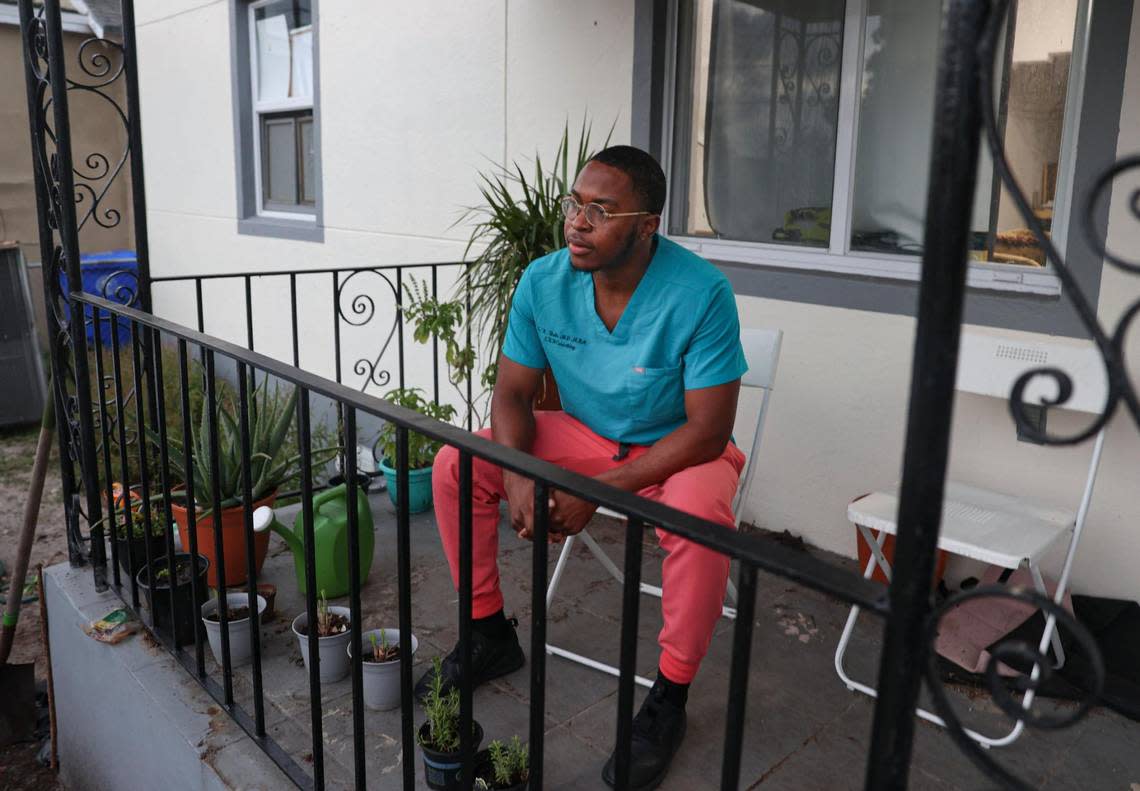 Dr. Lawrence Rolle, who is pictured on his porch in Miami after a day of work, is a second-year resident at Jackson Memorial Hospital. With all the cash bidders, it was a challenge for him to finally buy a house in Liberty City.