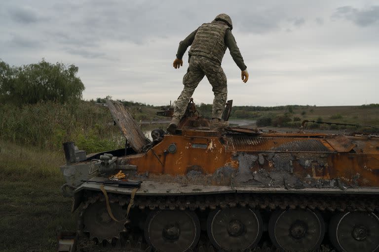 Un militar ucraniano se encuentra sobre un vehículo blindado ruso destruido en una zona retomada cerca de la frontera con Rusia en la región de Kharkiv, Ucrania, el sábado 17 de septiembre de 2022. (AP Photo/Leo Correa)