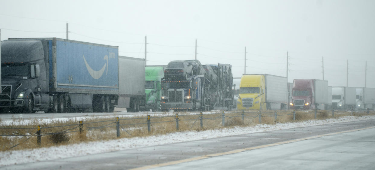 Tractor trailers are stacked up on the shoulder along the eastbound lanes of Interstate 70 near East Airpark Road, Tuesday, Dec. 13, 2022, in Aurora, Colo. A massive winter storm has closed roads throughout northeast Colorado. (AP Photo/David Zalubowski)