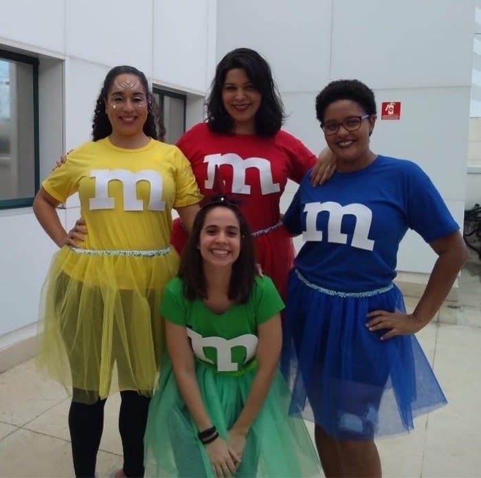 Four people, each dressed as a differently colored M&M