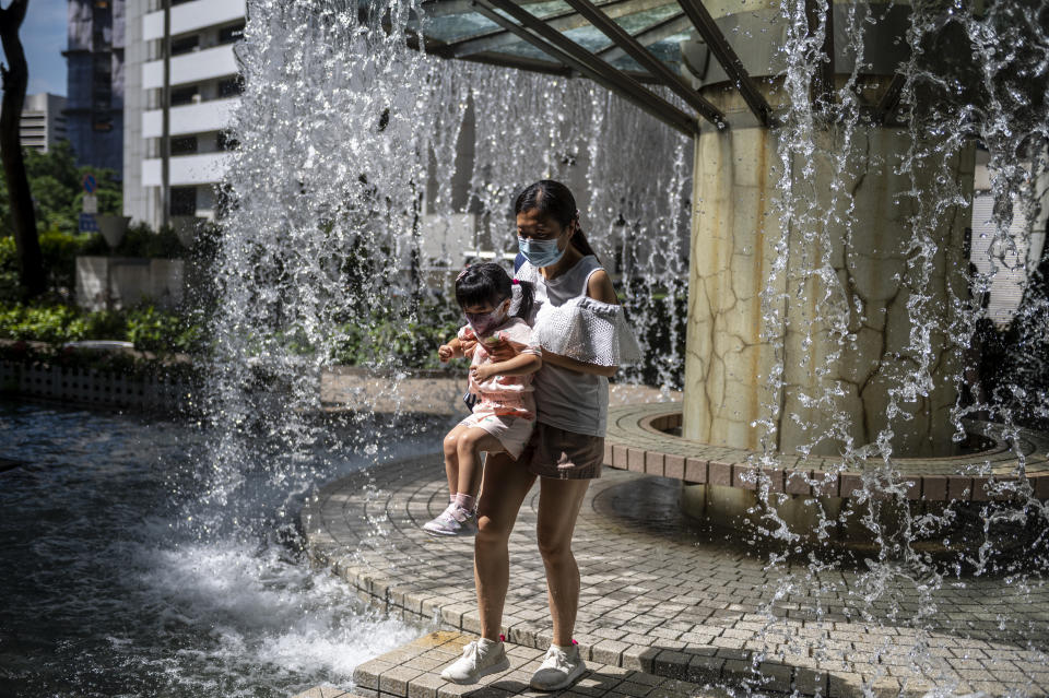 A women holding a girls walks out of a gazebo water fountain on August 27, 2022 in Hong Kong, China.  (Photo by Vernon Yuen/NurPhoto via Getty Images)