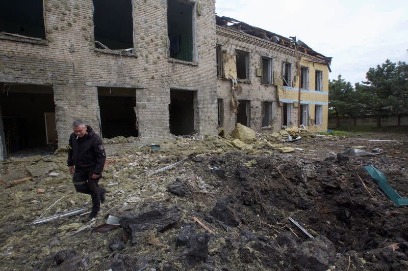 Un oficial de policía camina junto a un edificio escolar dañado por un ataque militar ruso en la región de Donetsk