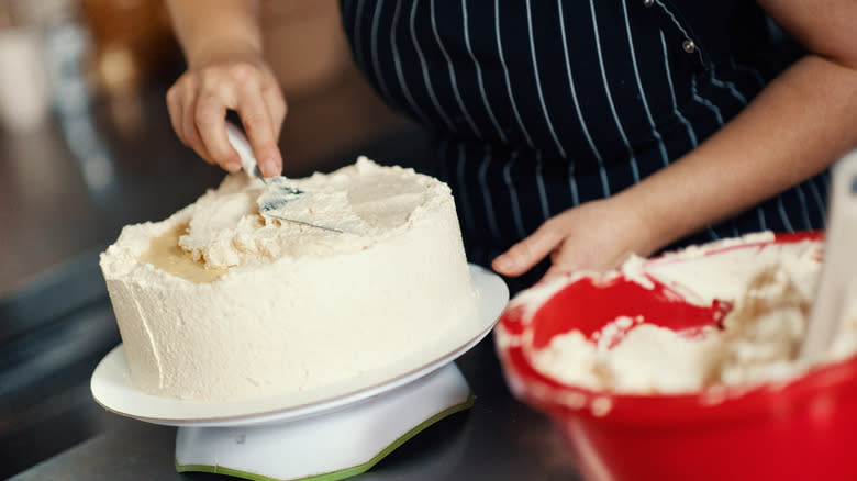 person frosting a cake