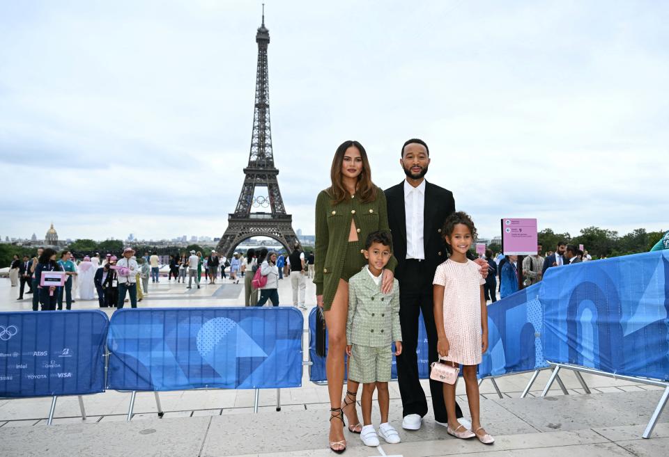 US singer-songwriter John Legend (R), his spouse US model Chrissy Teigen (L) and two of thier children arrive ahead of the opening ceremony of the Paris 2024 Olympic Games in Paris on July 26, 2024, as the Eiffel Tower is seen in the background. (Photo by Jonathan NACKSTRAND / AFP) (Photo by JONATHAN NACKSTRAND/AFP via Getty Images)