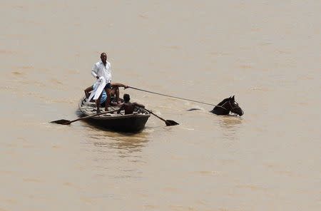 A man rows a boat as they pull out a horse from the flooded river Ganga in Allahabad, India, July 9, 2016. REUTERS/Jitendra Prakash