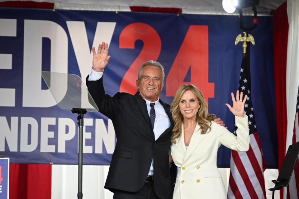 Robert F. Kennedy Jr. smiles and waves next to Cheryl Hines.