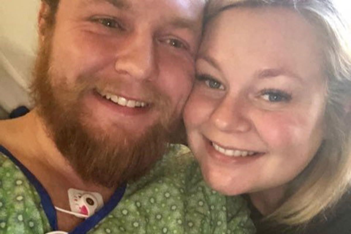 In this Tuesday, Oct. 23, 2018, photo Andrew Goette and his wife, Ashley,  look at their baby, Lennon, at United Hospital in Saint Paul, Minn. Andrew  awoke from a medically-induced coma just