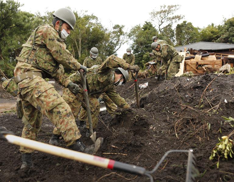 Members of Japan's Ground Self-Defense Force search for missing people on October 21, 2013 after a landslide caused by heavy rains from Typhoon Wipha lashed Oshima island