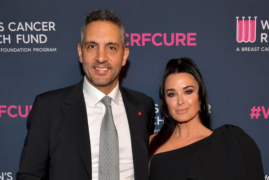 Kyle Richards and Mauricio Umansky posing in front of a step and repeat.