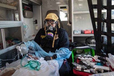 Empress EMS Capt. AJ Briones, wearing a personal protective equipment respirator (PPE), cares for a suspected COVID-19 patient while in route by ambulance to St. John's Riverside Hospital in Yonkers on April 6, 2020.