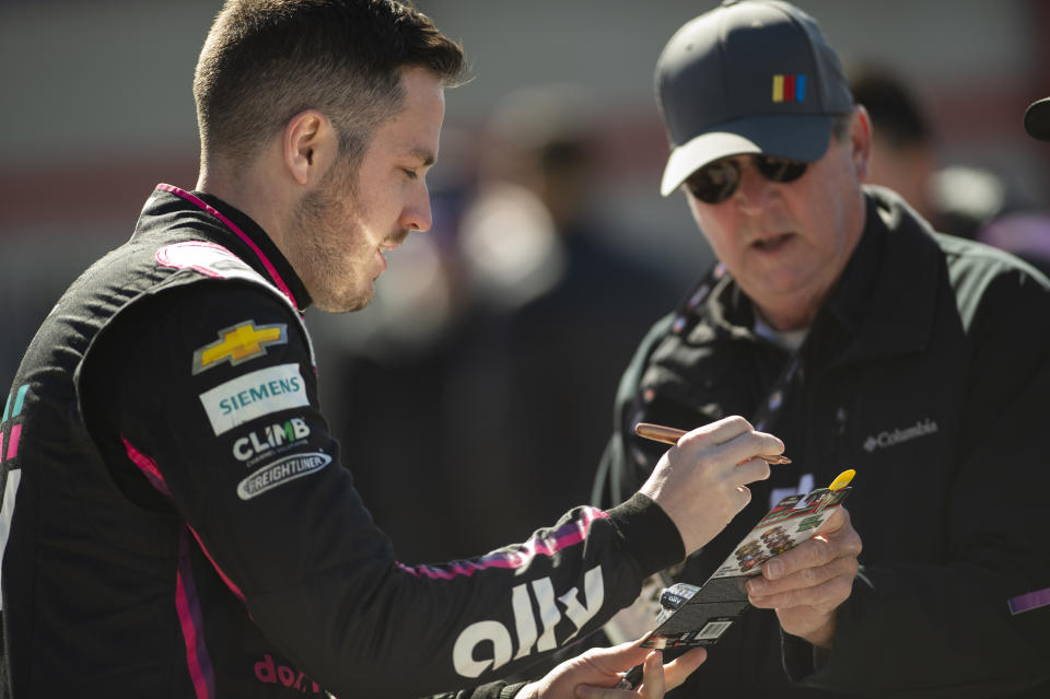 Driver Alex Bowman, left, signs autograph before qualifying for the NASCAR Cup Series auto race at Atlanta Motor Speedway on Saturday, March 18, 2023, in Hampton, Ga. (AP Photo/Hakim Wright Sr.)