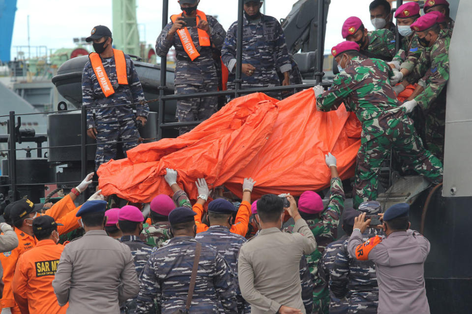 Officers lift a bag containing debris of the Sriwijaya Air plane which had just been unloaded from the Indonesian Navy ship.