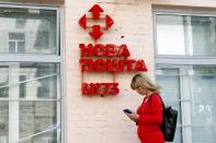 Woman stands next to a branch of the Nova Poshta (New Post) delivery service in Kyiv