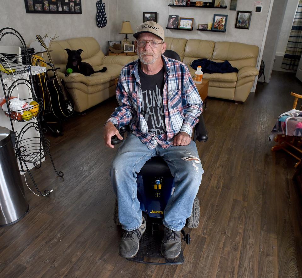 Army veteran Kenneth Clelland of Carleton is pictured in his mobile home with the wheelchair that was loaned to him by Binson’s Medical Equipment & Supplies in Macomb County. Behind is Shelby, a 4-year-old black Labrador and shepherd mix, who loves to play ball and eat hot dogs for a treat.