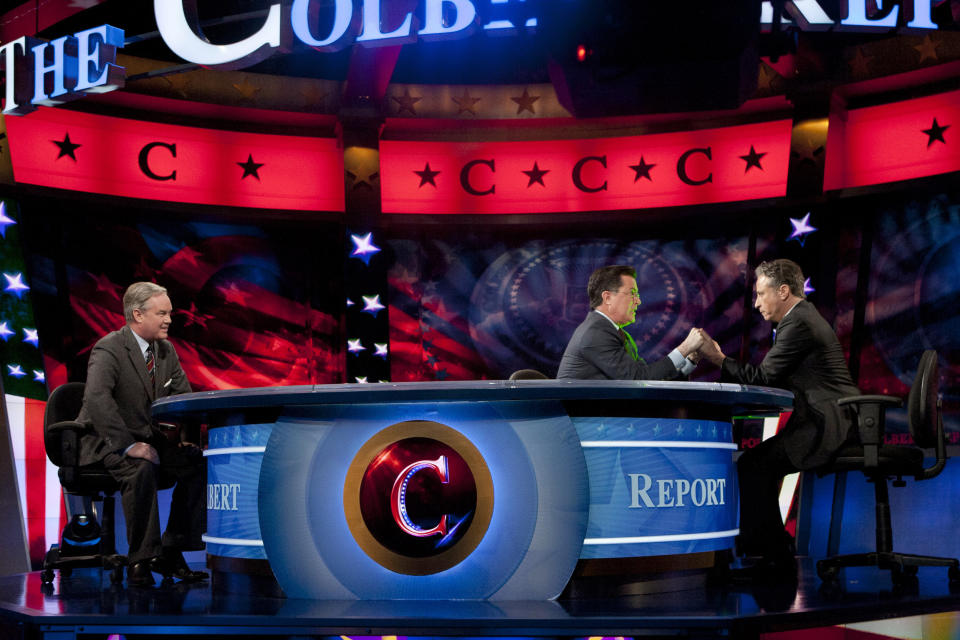 CORRECTS SPELLING OF STEWART'S FIRST NAME TO JON, NOT JOHN - In this photo provided by Comedy Central, Stephen Colbert, center, and Jon Stewart, right, hold hands during The Colbert Report, as Trevor Potter looks on Thursday, Jan. 12, 2012, in New York. During the episode, Colbert legally transferred his super political action committee to Stewart, his friend and Comedy Central cohort. Dropping by from "The Daily Show," Stewart happily signed the documents and accepted the post, which was ceremonially observed by the two holding hands and bodily transferring the PAC powers. (AP Photo/Comedy Central, Kristopher Long)