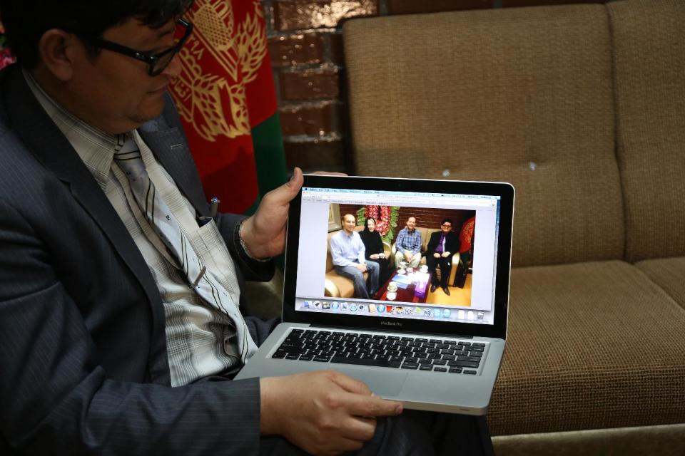 CORRECTS SPELLING OF NAME TO JOHN. Mohammad Hadi Hadayati, Kabul University's vice chancellor shows a photograph, from left, slain American John Gabel, his mother, his father Gary Gabel, who was also killed, and himself, during an interview with the Associated Press in Kabul, Afghanistan, Saturday, April 26, 2014. An Afghan police security guard opened fire on foreigners, on Thursday, April 24, 2014, as they entered the grounds of Cure International Hospital, killing three people, including pediatrician Dr. Jerry Umanos of Chicago. On Saturday, Kabul University vice chancellor Mohammad Hadi Hadayati identified the other two Americans killed in the attack as health clinic administrator John Gabel and his visiting father, Gary, also from the Chicago area. John Gabel’s wife, also an American, was wounded, Hadayati said. “We have lost a great man, a great teacher, a man who was here only to serve the Afghan people,” Hadayati said. John Gabel worked for the U.S.-based charity Morning Star Development and ran a health clinic at Kabul University, teaching computer science classes in his spare time, Hadayati said. John Gabel’s parents were visiting from Chicago, and Hadayati had lunch with the whole family the day before the attack. (AP photo/Rahmat Gul)