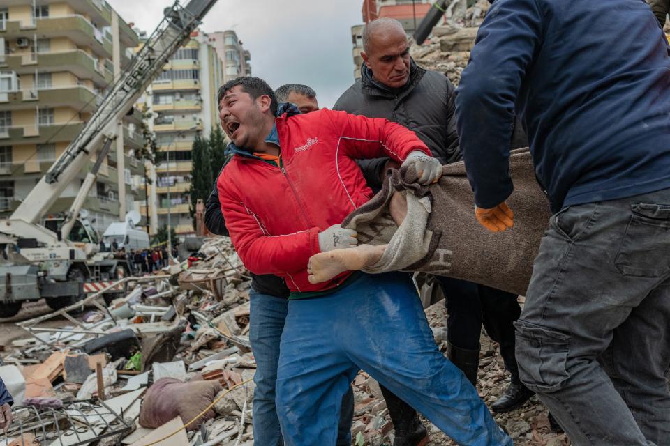 A rescuer reacts as he carries a body found in the rubble in Adana, Turkey