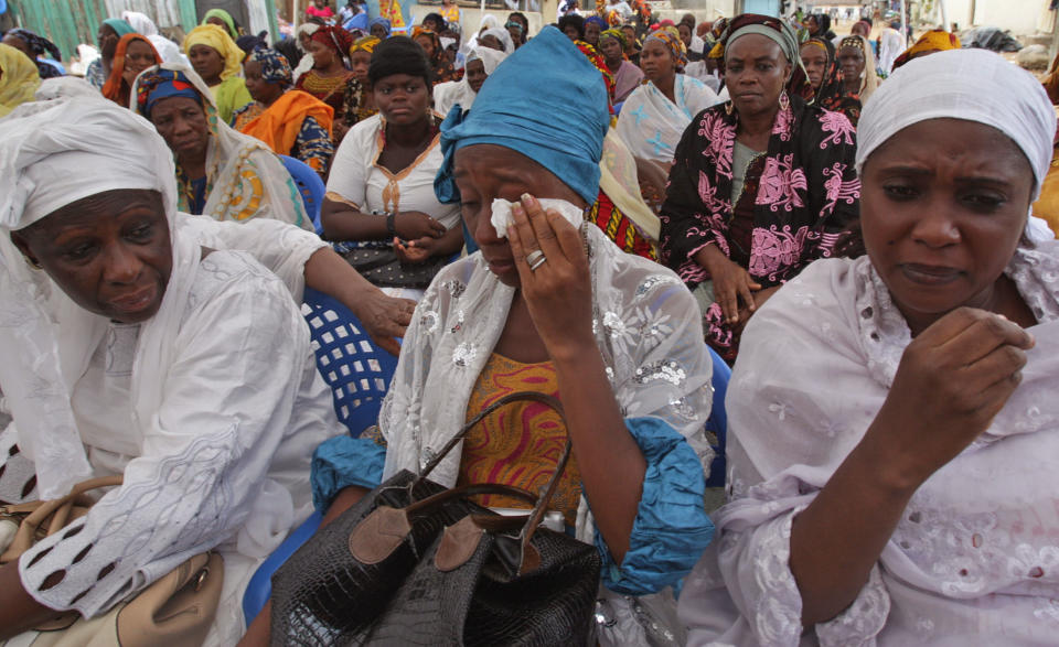 In this photo taken on Wednesday, April 2, 2014, Sira Kone Fadiga, right, the aunt of Ivorian fashion model Awa Fadiga, at her funeral with unidentified family members in Abidjan, Ivory Coast. Awa Fadiga was attacked at night in a taxi that was taking her home to an upscale neighborhood in Ivory Coast’s capital. Two witnesses say they saw the locally famous fashion model being thrown out of the cab under a bridge, apparently unconscious. Firefighters rushed the 23-year-old to the Central University Hospital where she was left untreated for more than 12 hours and slipped into a coma _ all because there was no one immediately available to pay her medical fees, her family said. (AP Photo/Sevi Herve Gbekide )