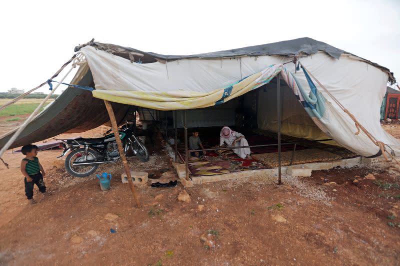 Abu Ghazl, a 53-year-old internally displaced man, sits inside his tent at a makeshift camp erected in a cemetery in Maarat Misrin