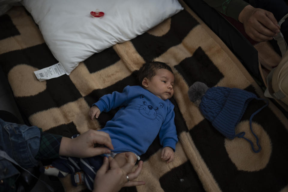 A baby who fled Ukraine, is cared for by his mother at a refugee center in Korczowa, Poland, Sunday, March 13, 2022. Now in its third week, the war has forced more than 2.5 million people to flee Ukraine. (AP Photo/Daniel Cole)