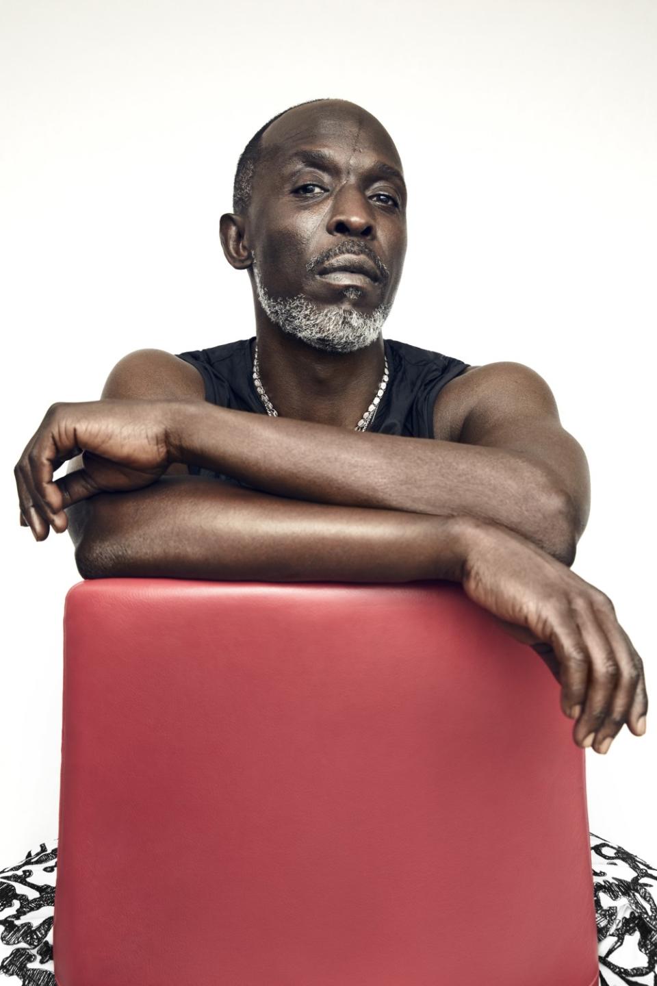 Michael K. Williams, perched over the back of a red chair.