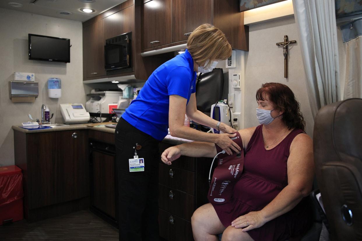 Claudia Portell (left) takes the blood pressure of Victoria Nelson during a checkup inside an Ascension St. Vincent's mobile health care clinic, which was visiting Lakeshore Baptist Church in Jacksonville. Portell is a registered nurse and the ministry's community outreach manager.