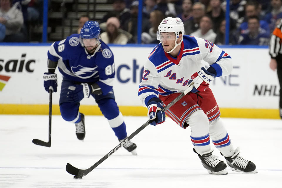 New York Rangers center Jonny Brodzinski (22) breaks out ahead of Tampa Bay Lightning right wing Nikita Kucherov (86) during the first period of an NHL hockey game Saturday, Dec. 30, 2023, in Tampa, Fla. (AP Photo/Chris O'Meara)