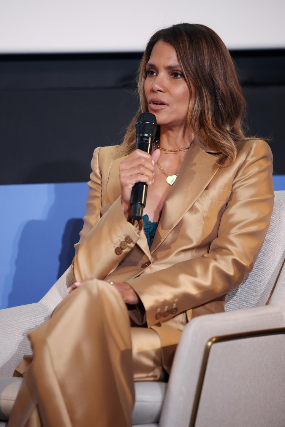 Halle in a tailored suit speaking into a microphone at an event