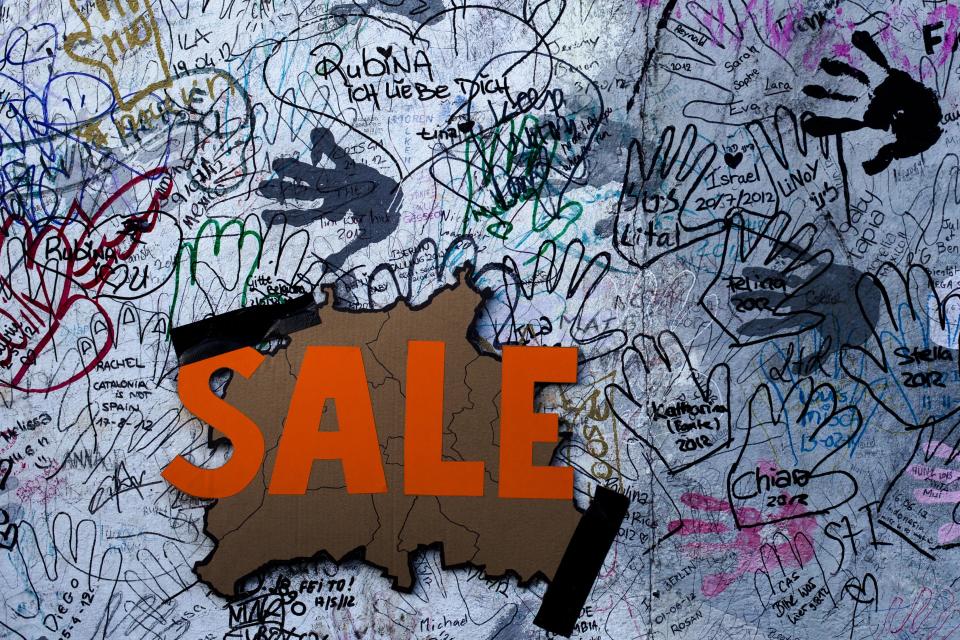 A 'Sale' sign with the form of Germany's capital Berlin is fixed amid graffiti on the East Side Gallery section of the former Berlin Wall in Berlin, Monday, March 4, 2013. After massive protest an investor suspended the removal of a section of the historic stretch of the Berlin Wall known as the East Side Gallery to provide access to a riverside plot where luxury condominiums are being built. (AP Photo/Markus Schreiber/Pool)