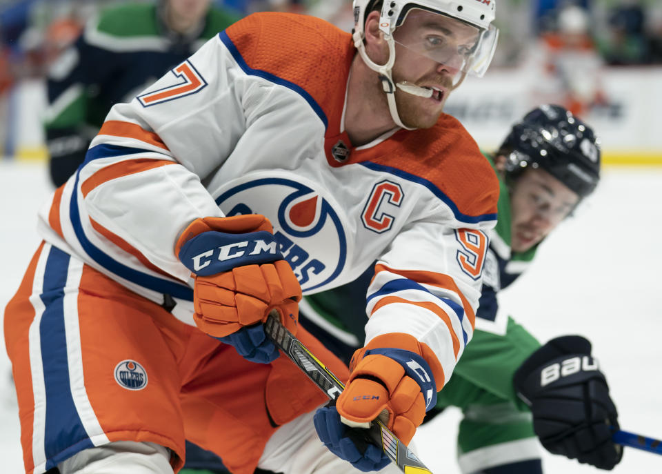 Edmonton Oilers centre Connor McDavid (97) fights for control of the puck with Vancouver Canucks defenseman Quinn Hughes (43) during the first period of an NHL hockey game Thursday, Feb. 25, 2021, in Vancouver, British Columbia. (Jonathan Hayward/The Canadian Press via AP)