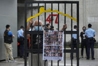 A protester stands behind a mock prison while police officers do search to other protesters during a protest against an election committee that will vote for the city's leader in Hong Kong Sunday, Sept. 19, 2021. Hong Kong's polls for an election committee that will vote for the city's leader kicked off Sunday amid heavy police presence, with chief executive Carrie Lam saying that it is "very meaningful" as it is the first election to take place following electoral reforms. (AP Photo/Vincent Yu)