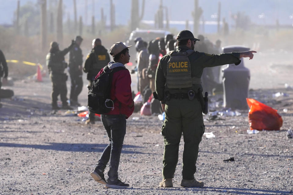 A migrant is directed by a member of U.S. Customs and Border Protection as hundreds of migrants gather along the border Tuesday, Dec. 5, 2023, in Lukeville, Ariz. (AP Photo/Ross D. Franklin)