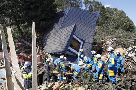 Rescue workers search for survivors from a house damaged by a landslide caused by an earthquake in Atsuma town, Hokkaido, Japan, in this photo taken by Kyodo September 6, 2018. Kyodo/via REUTERS