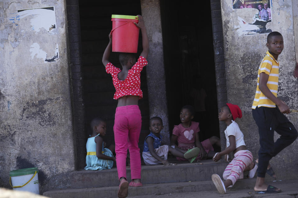 A young girl carries a bucket of water while entering a block of flats in Harare, Zimbabwe, Saturday Nov. 18, 2023. Zimbabwe is battling a cholera outbreak that has resulted in more than 150 suspected deaths countrywide. Health experts, authorities and residents blame the outbreak on acute water shortages and lack of access to sanitation and hygiene services (AP Photo/Tsvangirayi Mukwazhi)