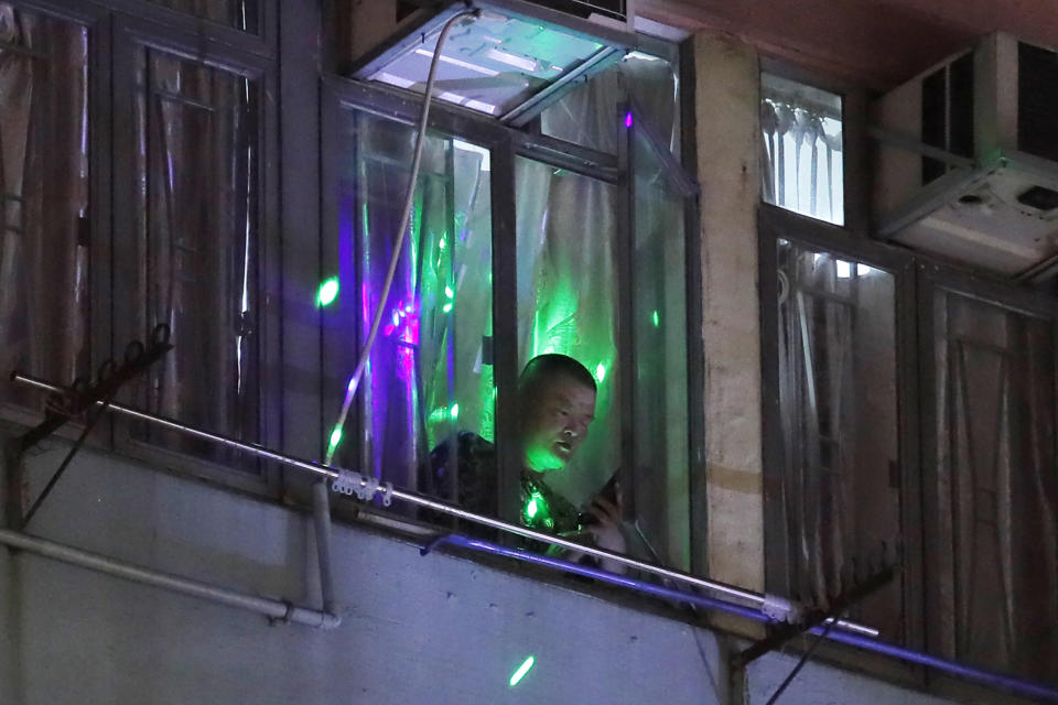 Protesters flash laser beams onto a man in a residential building as they think he is a pro-Beijing supporter in Hong Kong, Monday, Aug. 5, 2019. Droves of protesters filled public parks and squares in several Hong Kong districts on Monday in a general strike staged on a weekday to draw more attention to their demands that the semi-autonomous Chinese city's leader resign.(AP Photo/Kin Cheung)