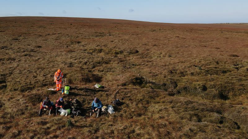 Contractors take a break on moorland whilst planting Sphagnum Moss as part of a conservation project on Black Ashop moor near Glossop